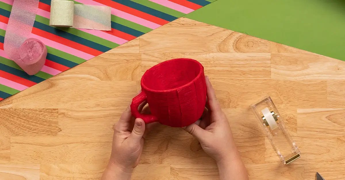 A mug completely covered in strips of red crepe paper.