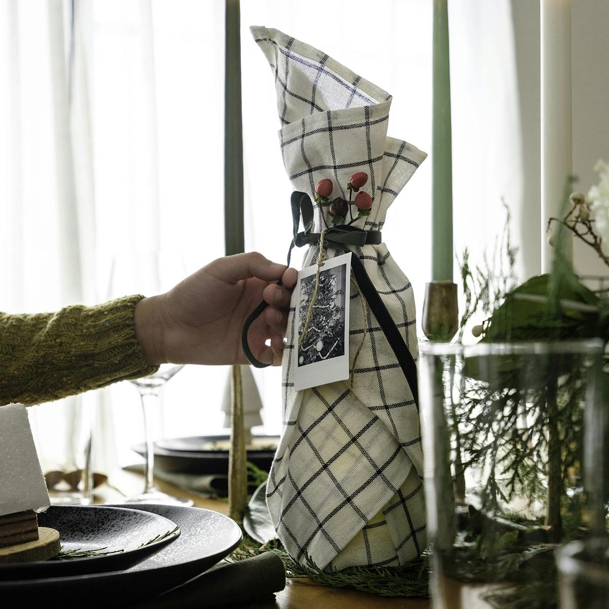 Wine bottle wrapped in a tea towel and placed on a Christmas dining table.