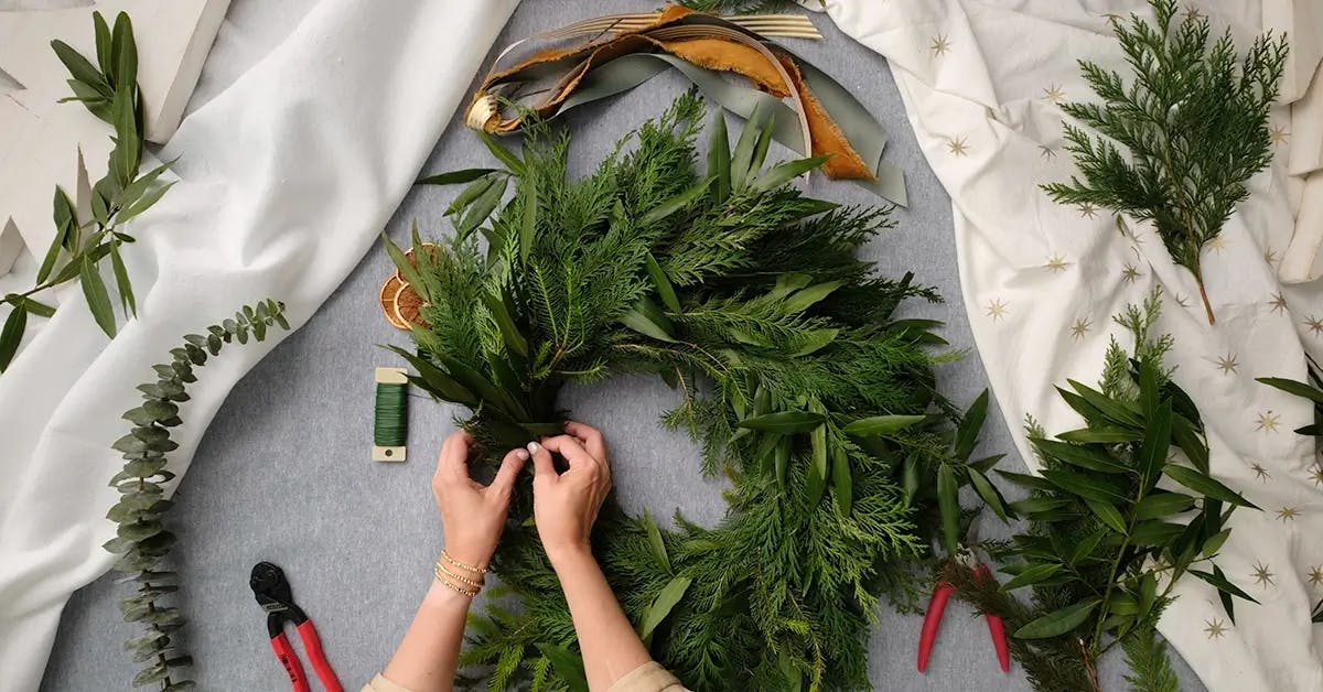 Adding the last bundle of greens to a Thanksgiving wreath.
