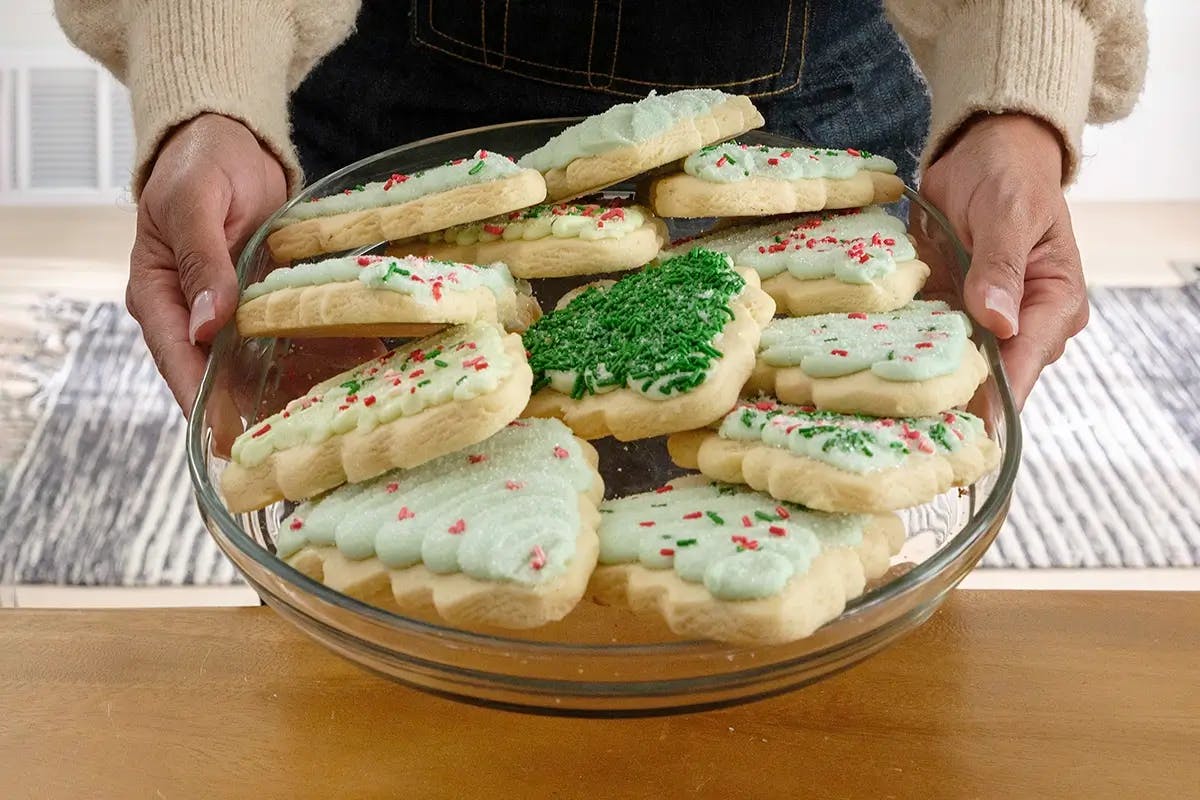 Hands holding a plate of cookies in an article containing Christmas cookie decorating tips.