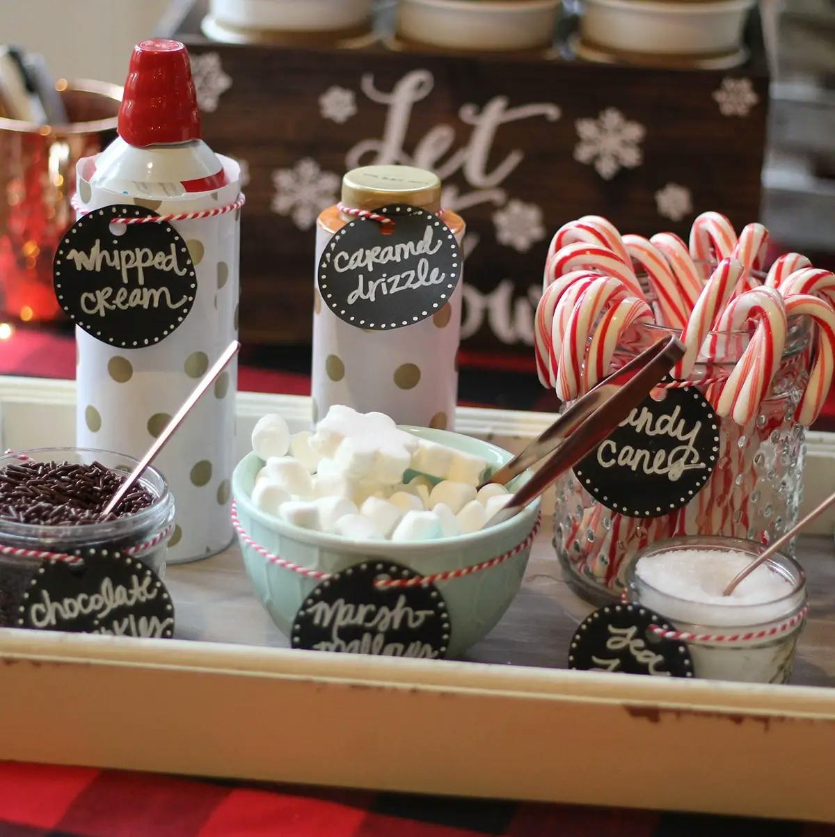 Hot chocolate topping station, showing whipped cream, caramel drizzle, candy canes, chocolate sprinkles, marshmallows, and sea salt.