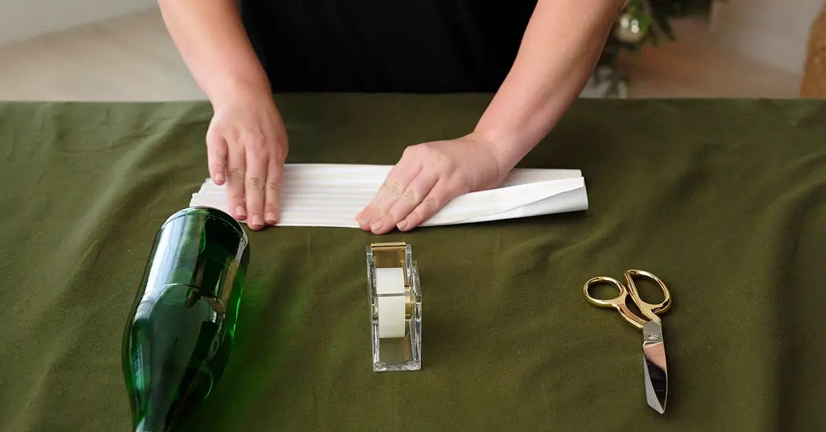 Cutting wrapping paper into 2” strips ready to wrap a wine bottle.