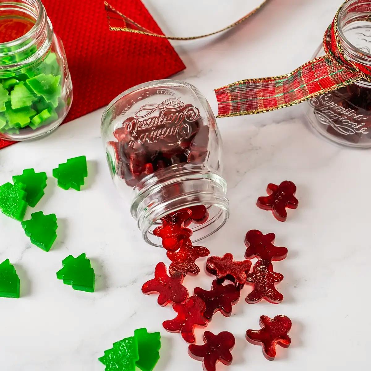 Red and green gummy Christmas candies spilling out of a jar on its side.