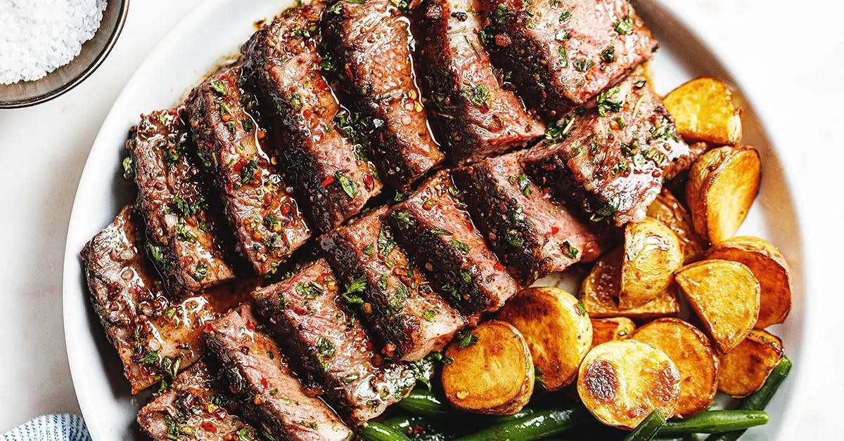 Slices of Garlic Herb Butter Steak with green beans and roast potatoes - part of a dinner recipe for two.