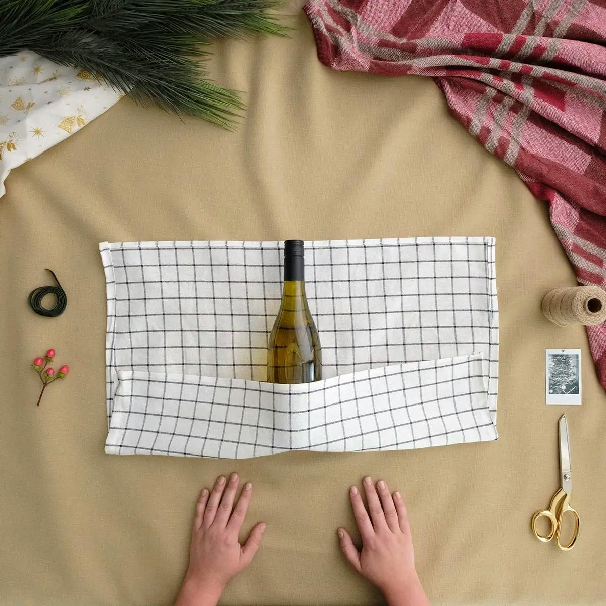 Folding the bottom of the tea towel over the base of the wine bottle.
