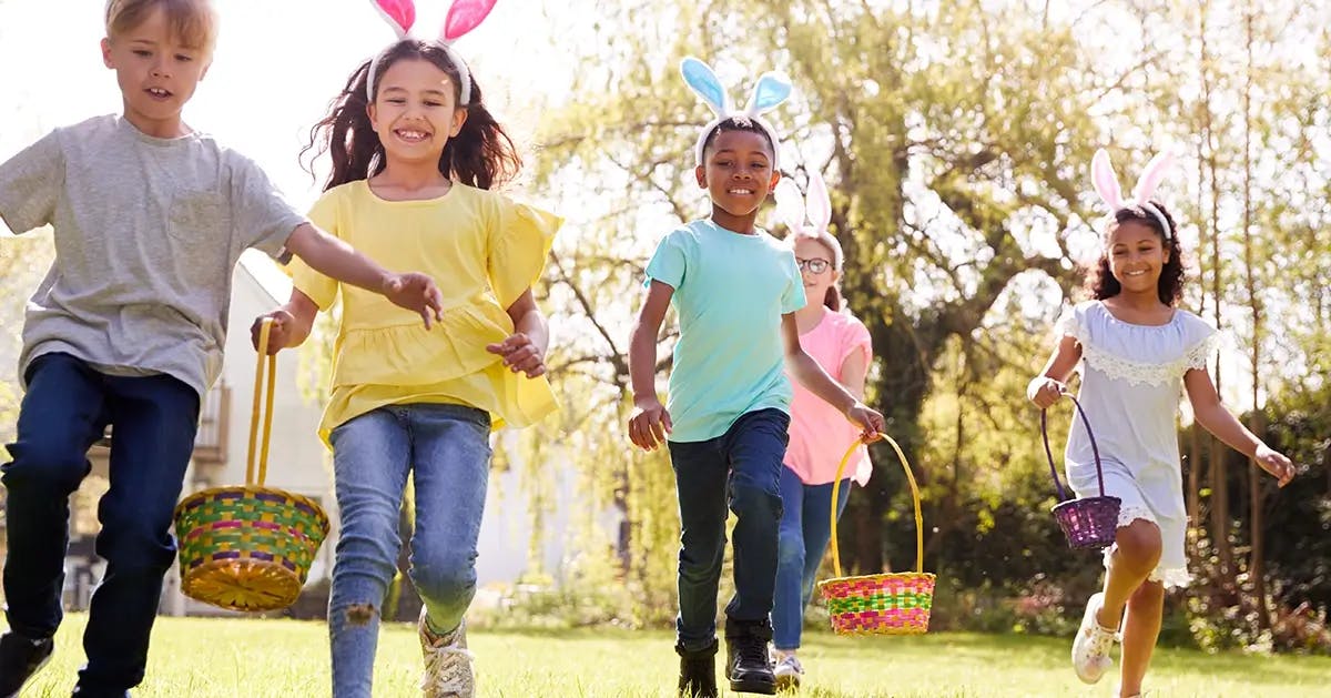 Children wearing bunny ears running to find easter eggs during an easter egg hunt.