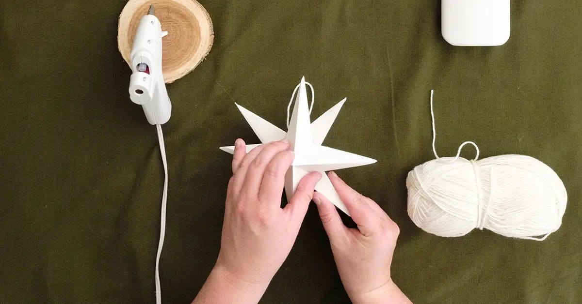 Connecting the two pieces of a paper star to make a Christmas tree topper.
