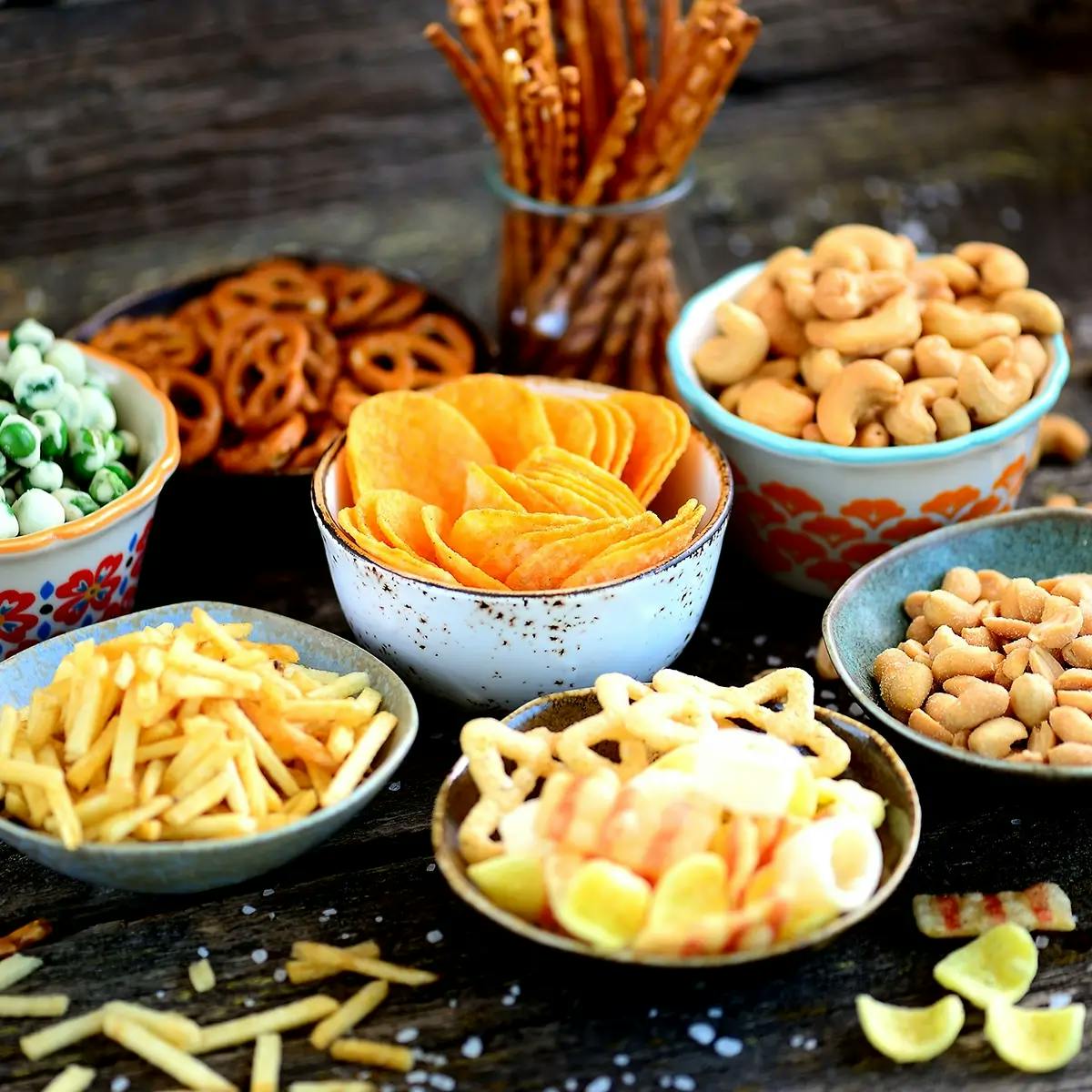 Bowls of Christmas snacks on a wooden table.