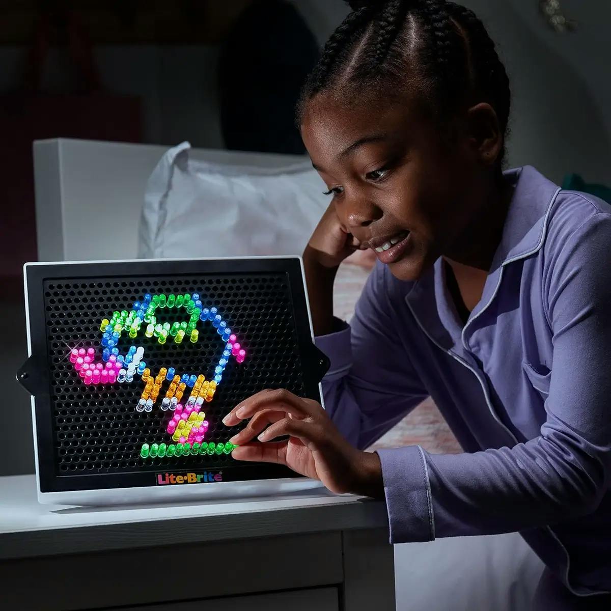 Black girl in pajamas playing with Lite Brite offline game for kids.