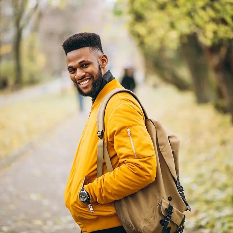 Black man in yellow jacket wearing backpack