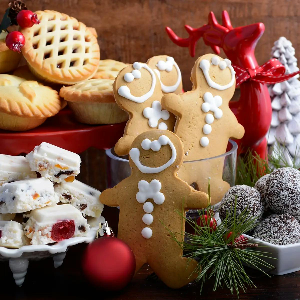 A Christmas dessert charcuterie board with mince pies, gingerbread men, truffles, and nougat.