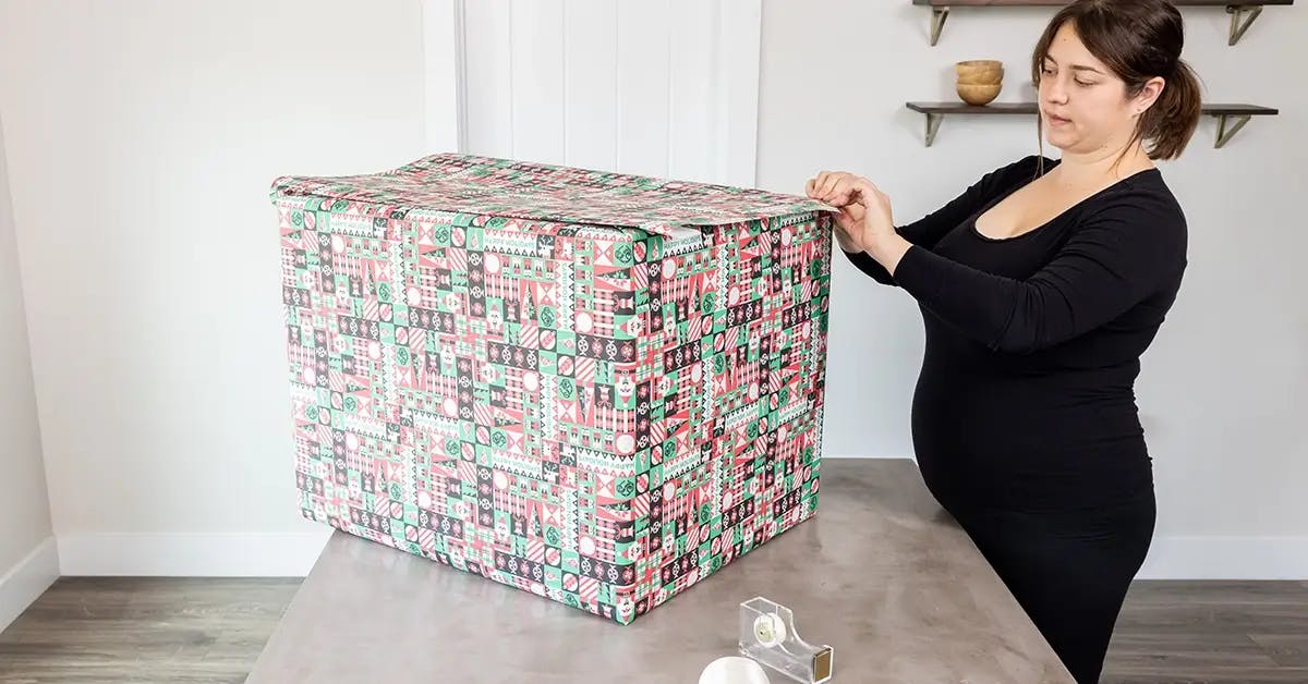 Covering a large box with wrapping paper.