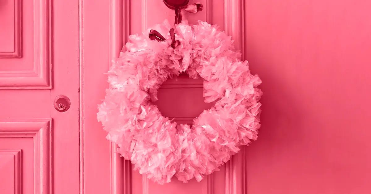 Bright pink double front door with pink wreath hanging from door adorned with a red ribbon.