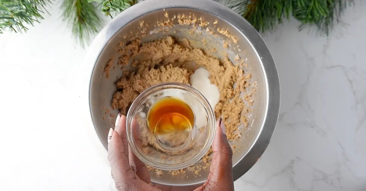 Adding dairy-free yogurt and vanilla extract to the mixture for vegan chocolate chip cookies.