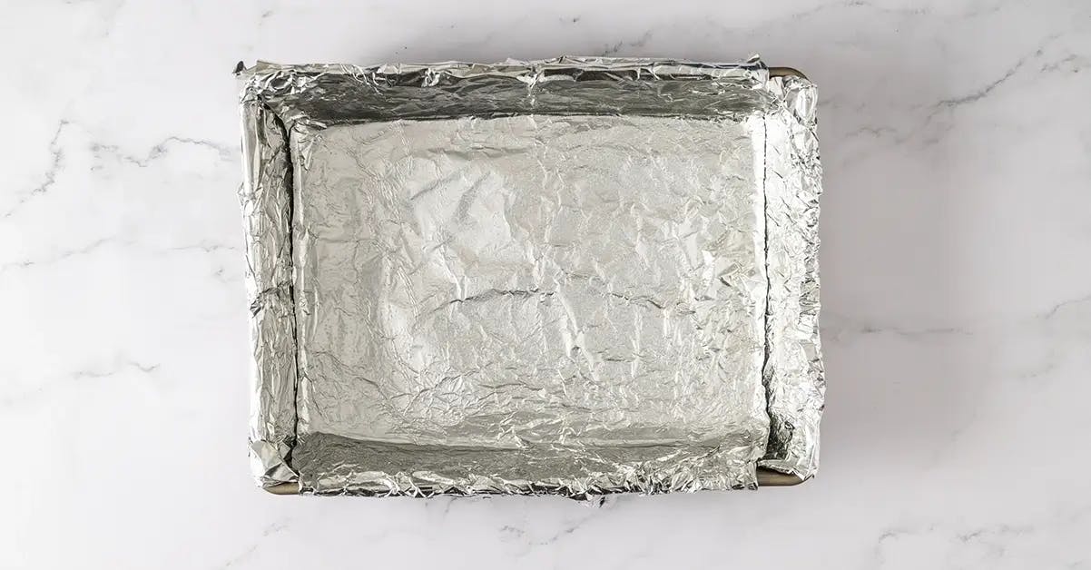 Lining a baking tin with foil ready to make homemade peppermint marshmallows.