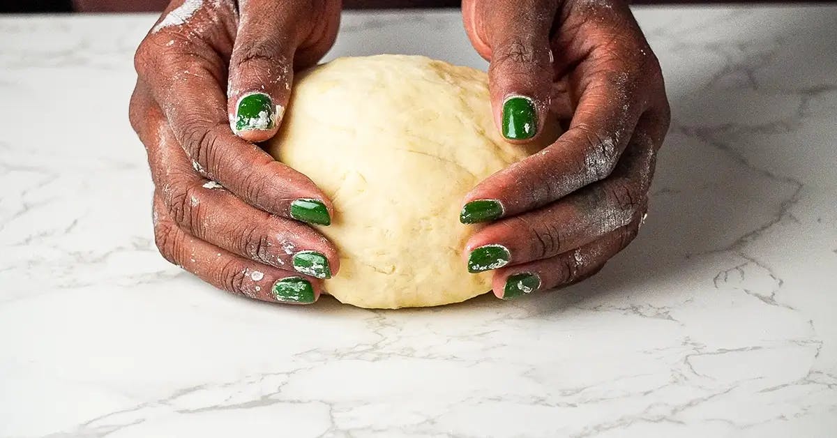Hands holding homemade dough for vegetarian lasagne recipe.