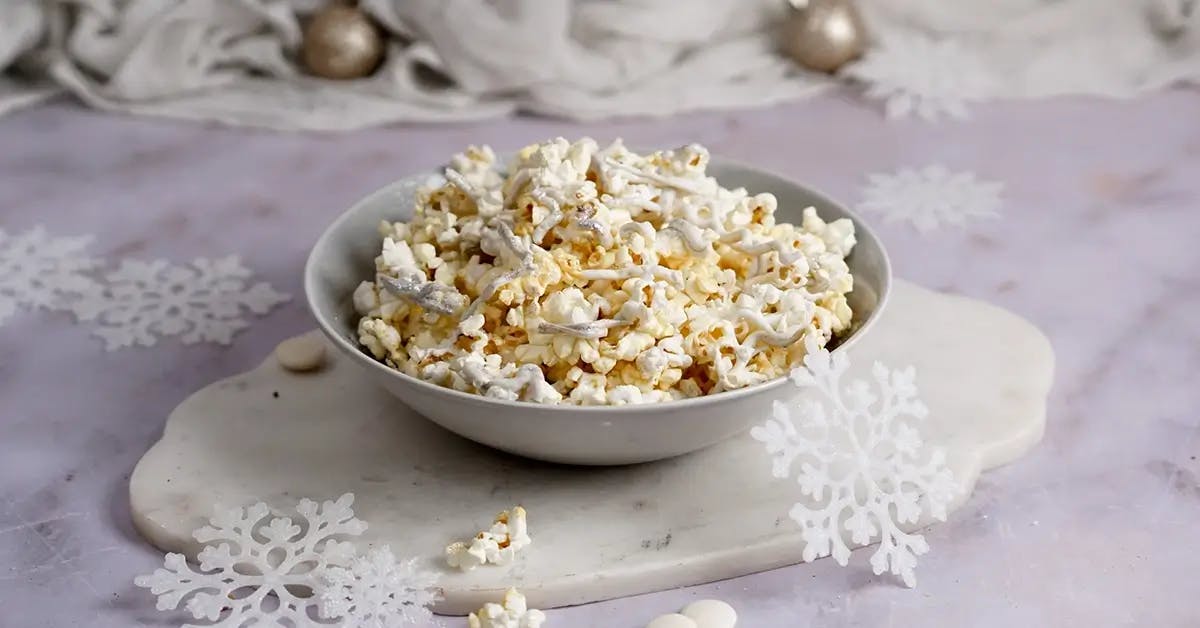 A bowl of Christmas popcorn drizzled with white chocolate and edible silver glitter.
