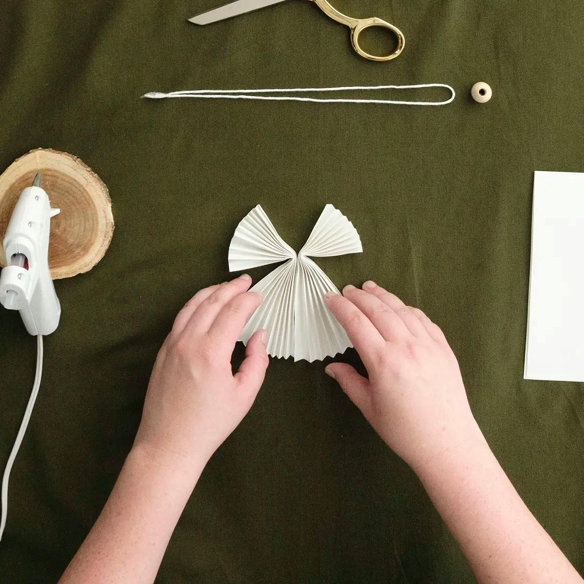 Joining folded paper to form a DIY Christmas angel ornament.