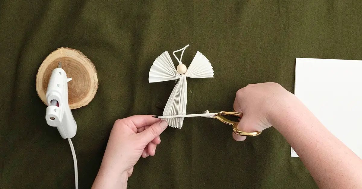 Trimming the wings and skirt of a DIY angel Christmas ornament.