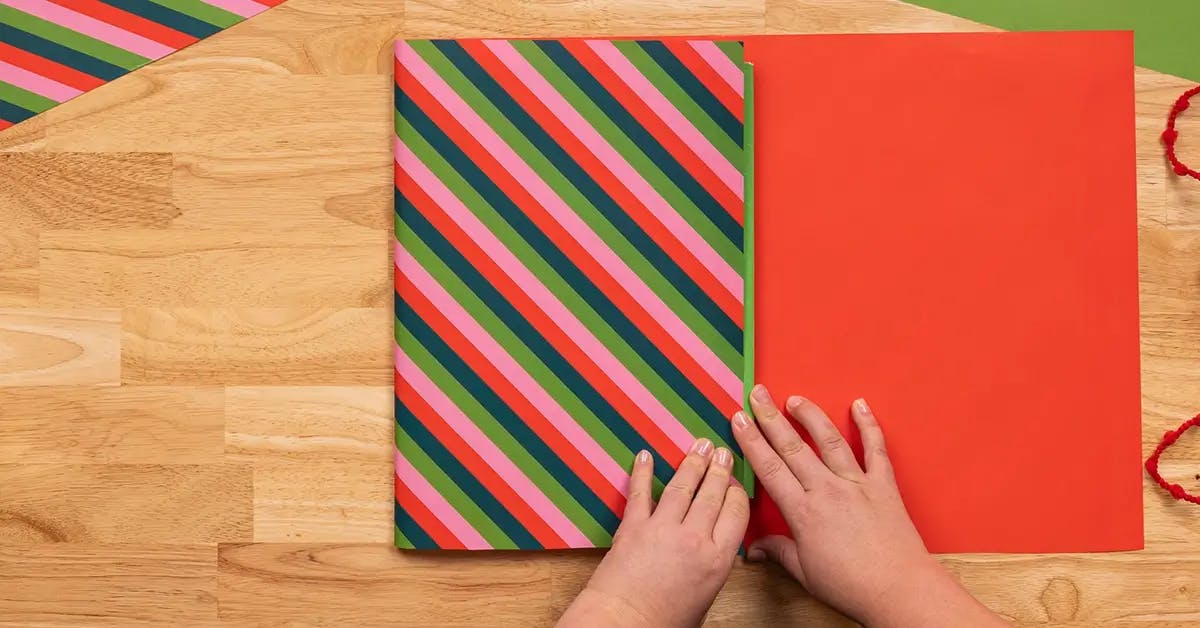 Folding wrapping paper to the edge of a book, in a tutorial on how to wrap a book.