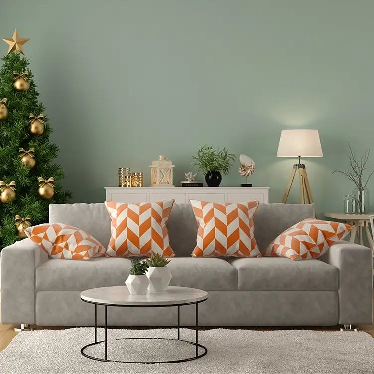 Grey living room sofa with orange chevron pillows, and Christmas tree in background.