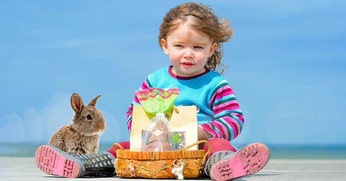 Toddler sitting on beach with Easter basket and bunny.