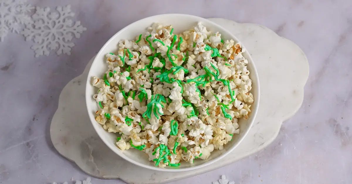 A bowl of Christmas popcorn drizzled with melted almond bark dyed green.