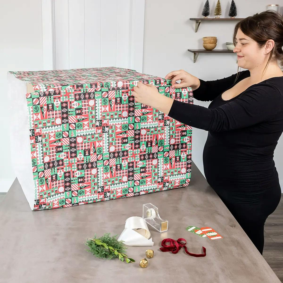 Securing wrapping paper to a large box with tape.
