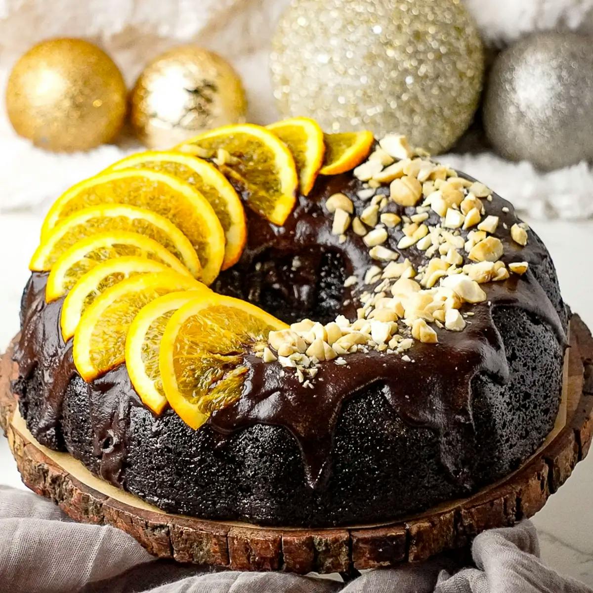 Vegan chocolate orange cake covered in vegan chocolate ganache and decorated with nuts and orange slices.