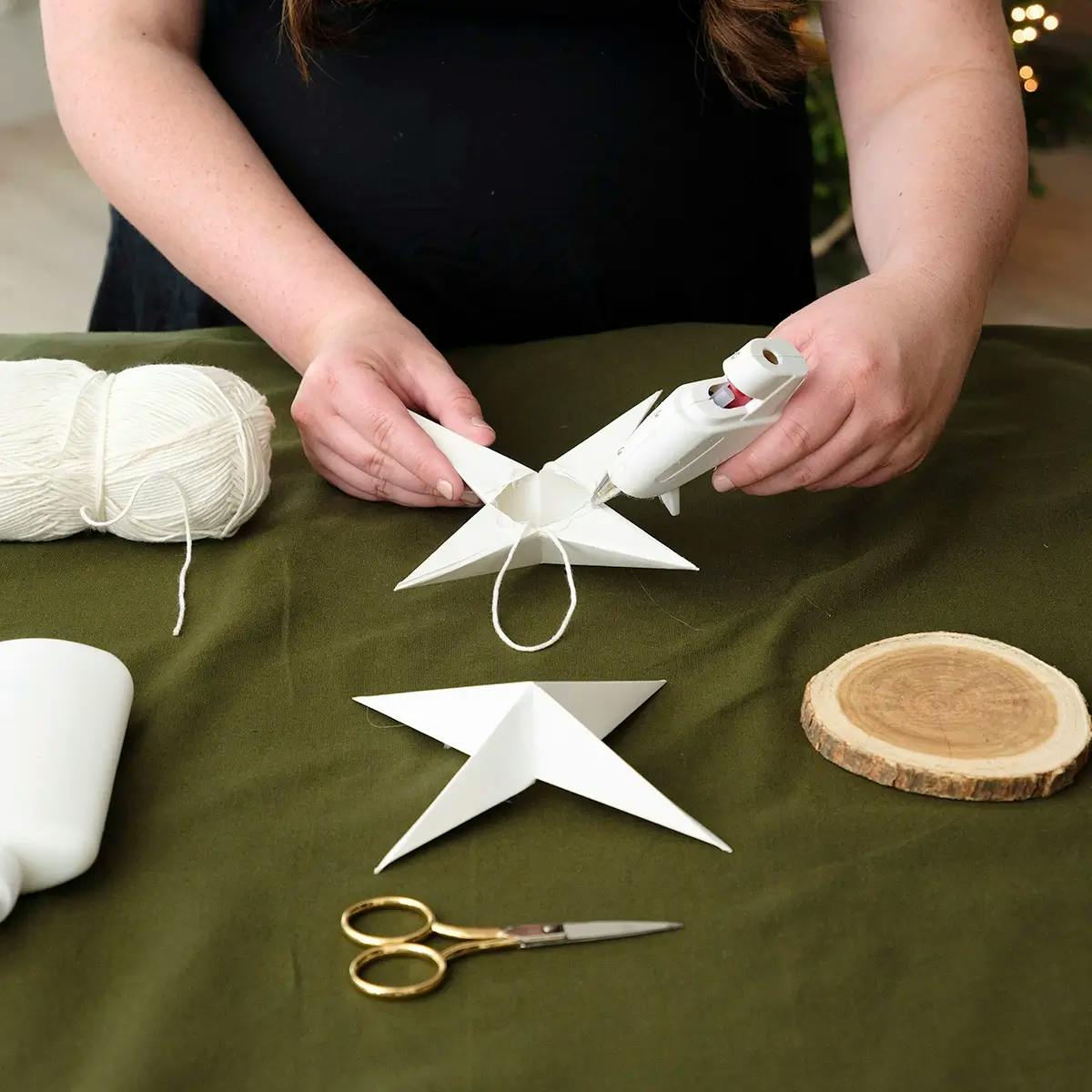 Adding twine to the center of a paper star tree topper.