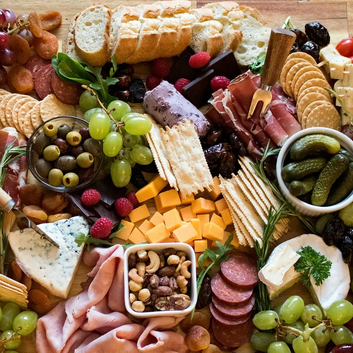 Christmas charcuterie board featuring meat, cheese, fruit, and crackers.
