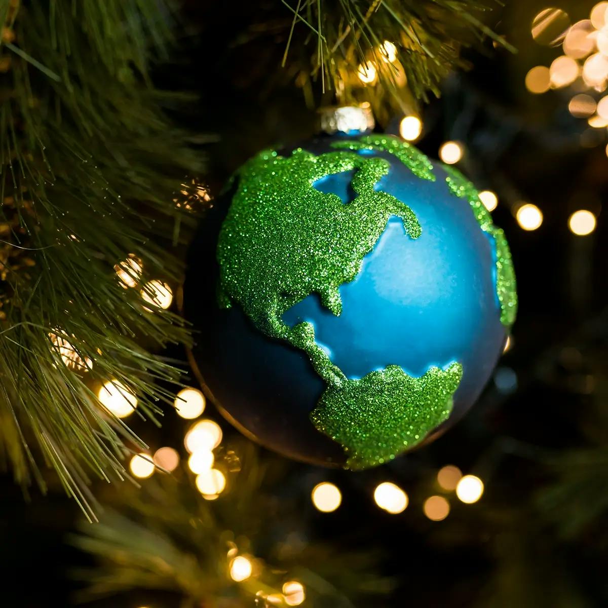 Close-up of Christmas ornament shaped like planet earth on the background of the Christmas tree.
