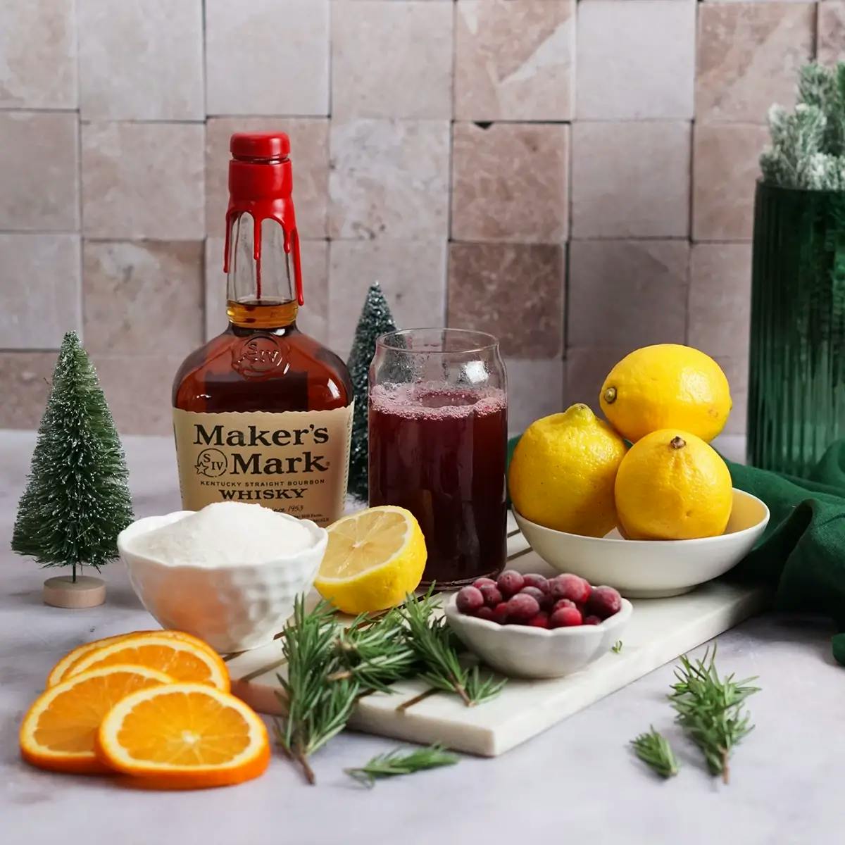 The ingredients for a Christmas punch recipe: Makers Mark bourbon, lemons, sugar, cranberries, and sliced oranges.