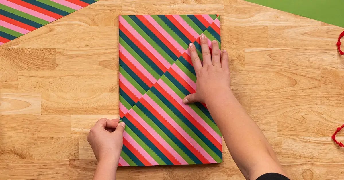 Making a fold in the wrapping paper to contain tags, floral accompaniments, and other decoration.