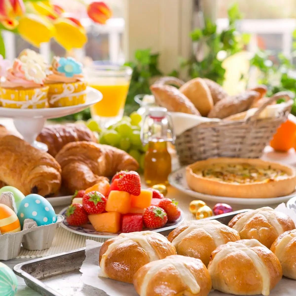 Spring table set for Easter brunch with fruit, croissants, and hot cross buns
