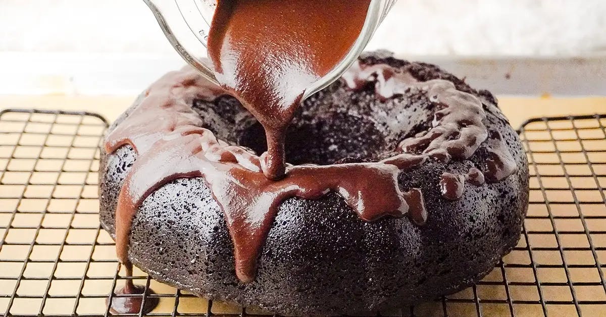 Pouring chocolate ganache over a vegan chocolate orange bundt cake.