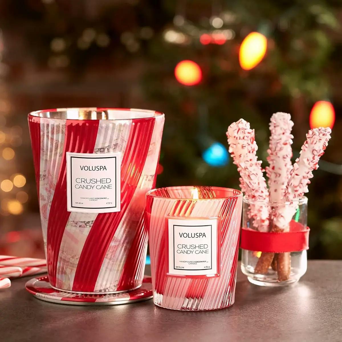 Two Voluspa Christmas candles scented like candy canes, with jars of peppermints and candy canes in the background.