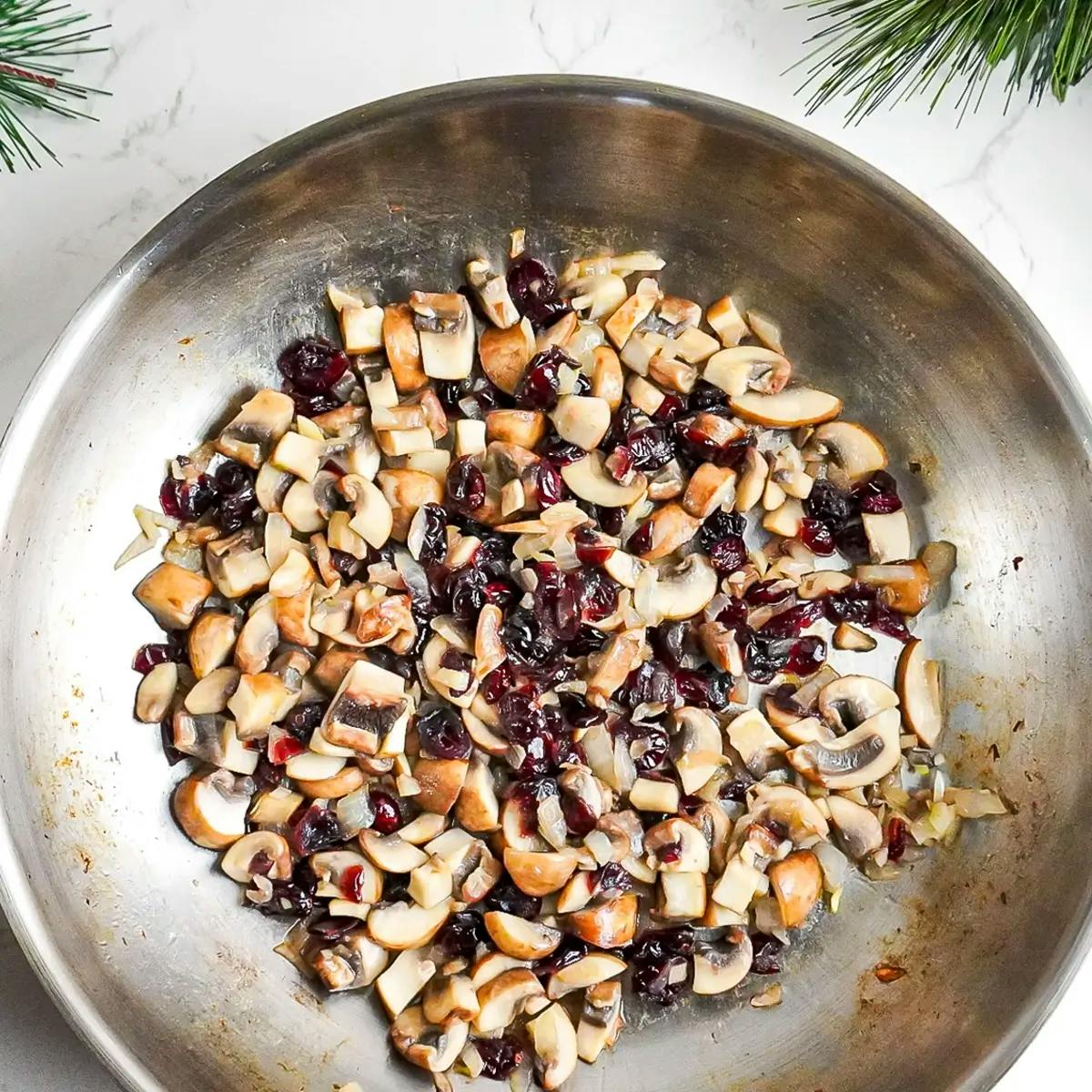 Adding mushrooms and dried cranberries to the seasoning for a vegan recipe with seitan.
