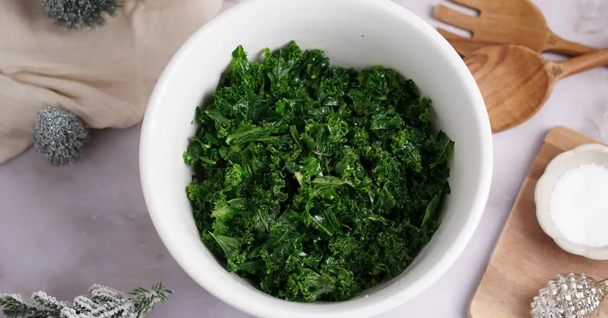 Massaging kale until soft, as part of a Thanksgiving salad recipe.