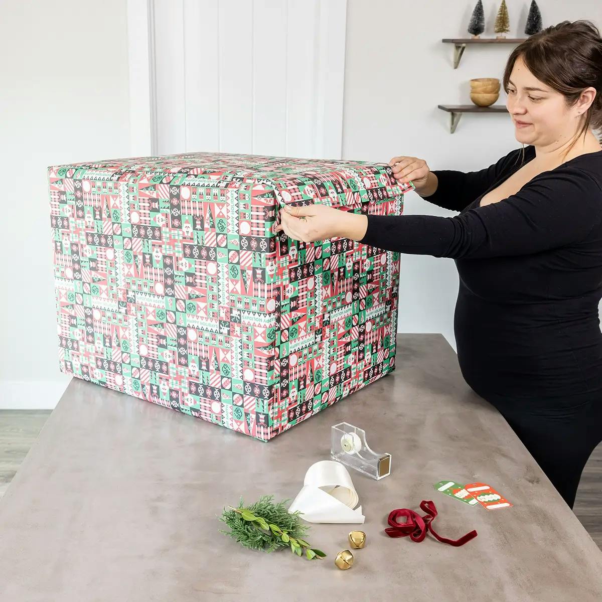 Filling in the blank spaces on a large box with Christmas wrapping paper.