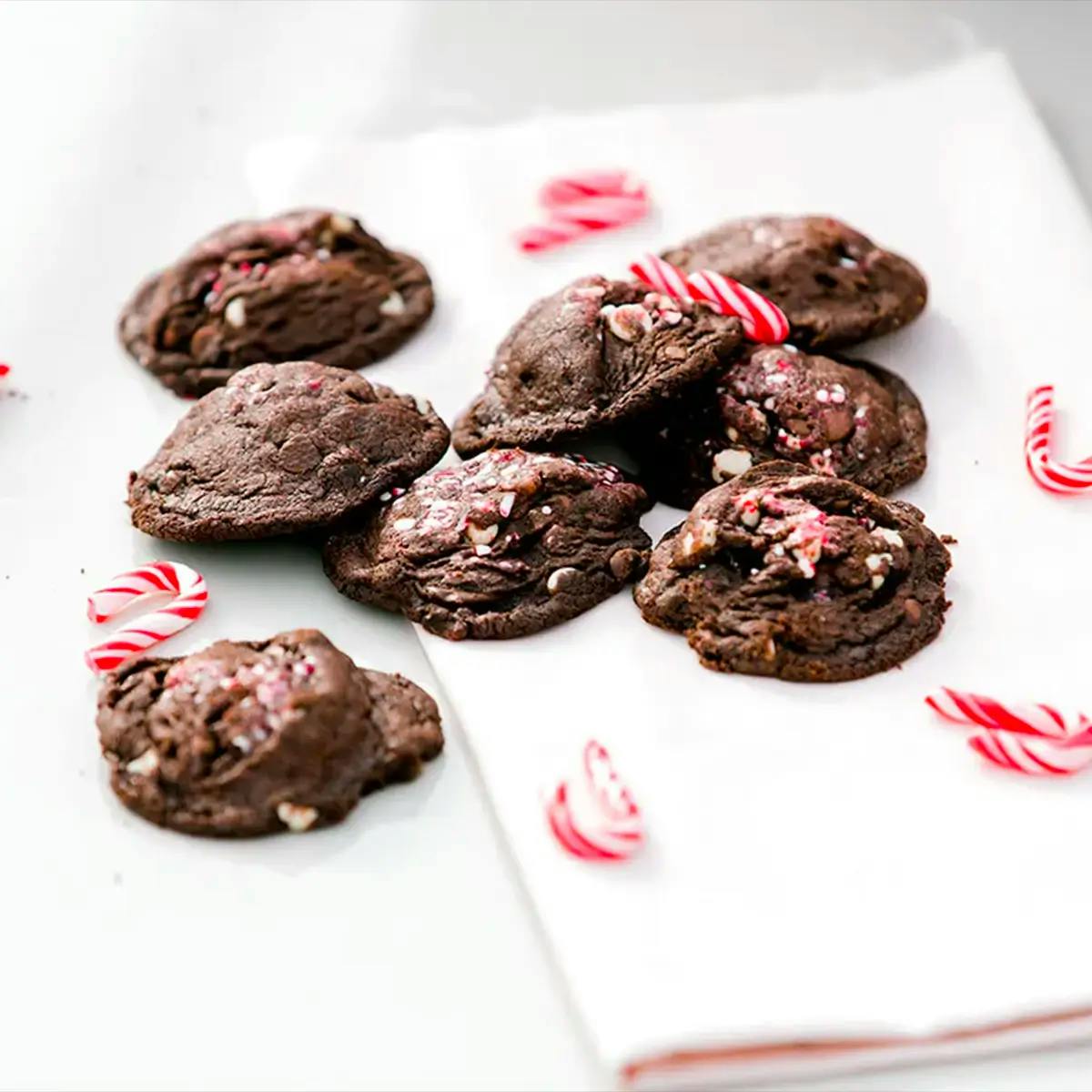 Chocolate peppermint cookies on a napkin, with candy canes scattered around.