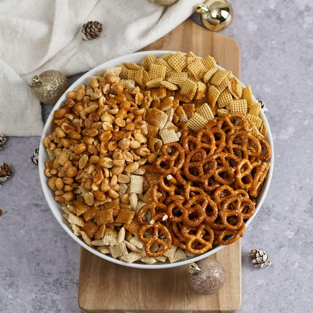 Rice chex, corn chex, pretzels and peanuts in a large bowl.