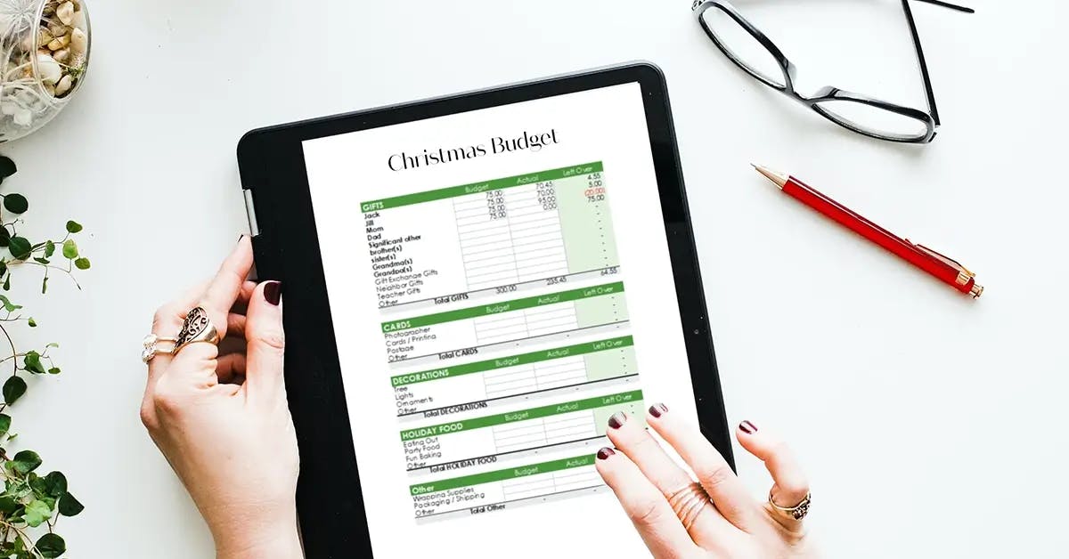Hands holding an iPad showing a Christmas budget spreadsheet
