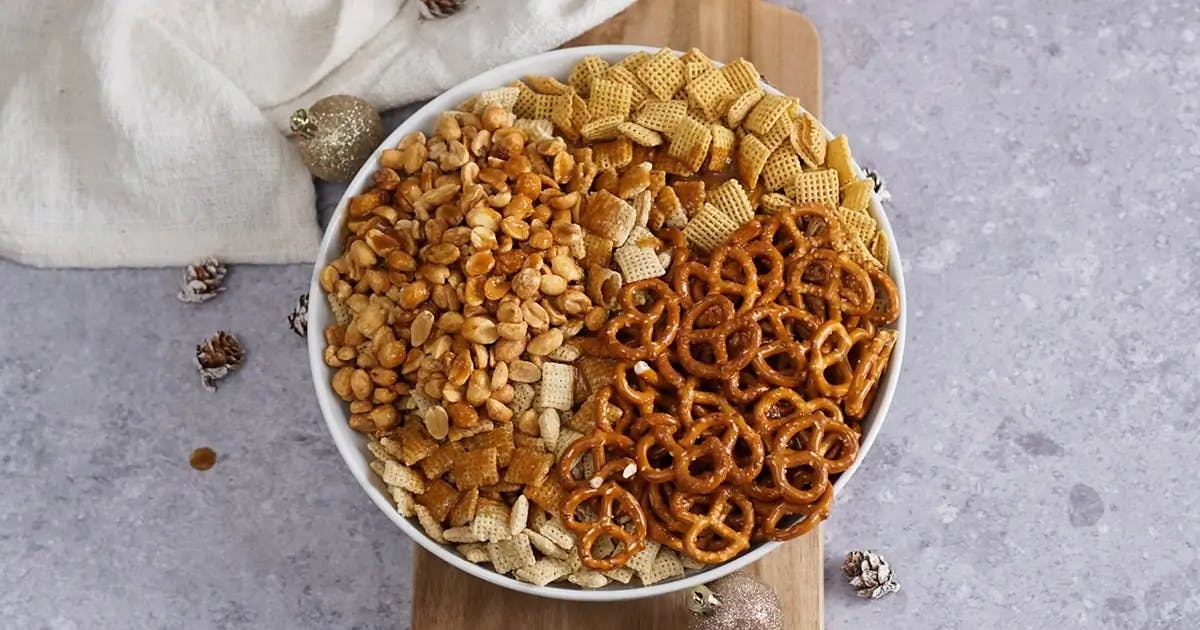 Rice chex, corn chex, pretzels and peanuts in a large bowl.