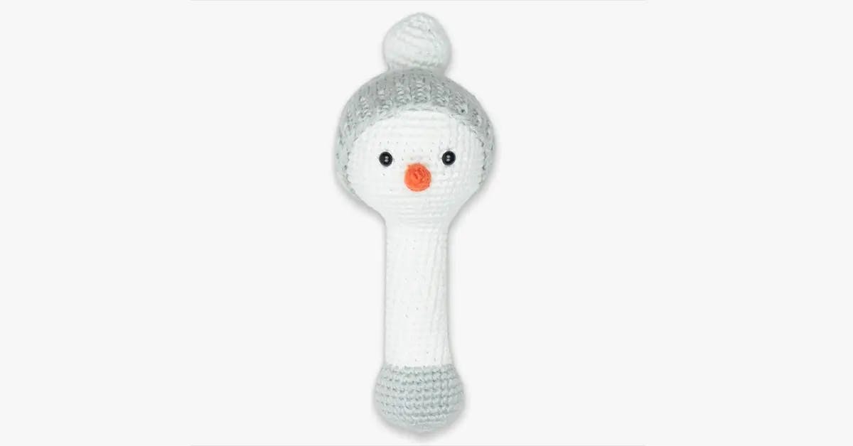 A white crochet children’s rattle shaped like a penguin.