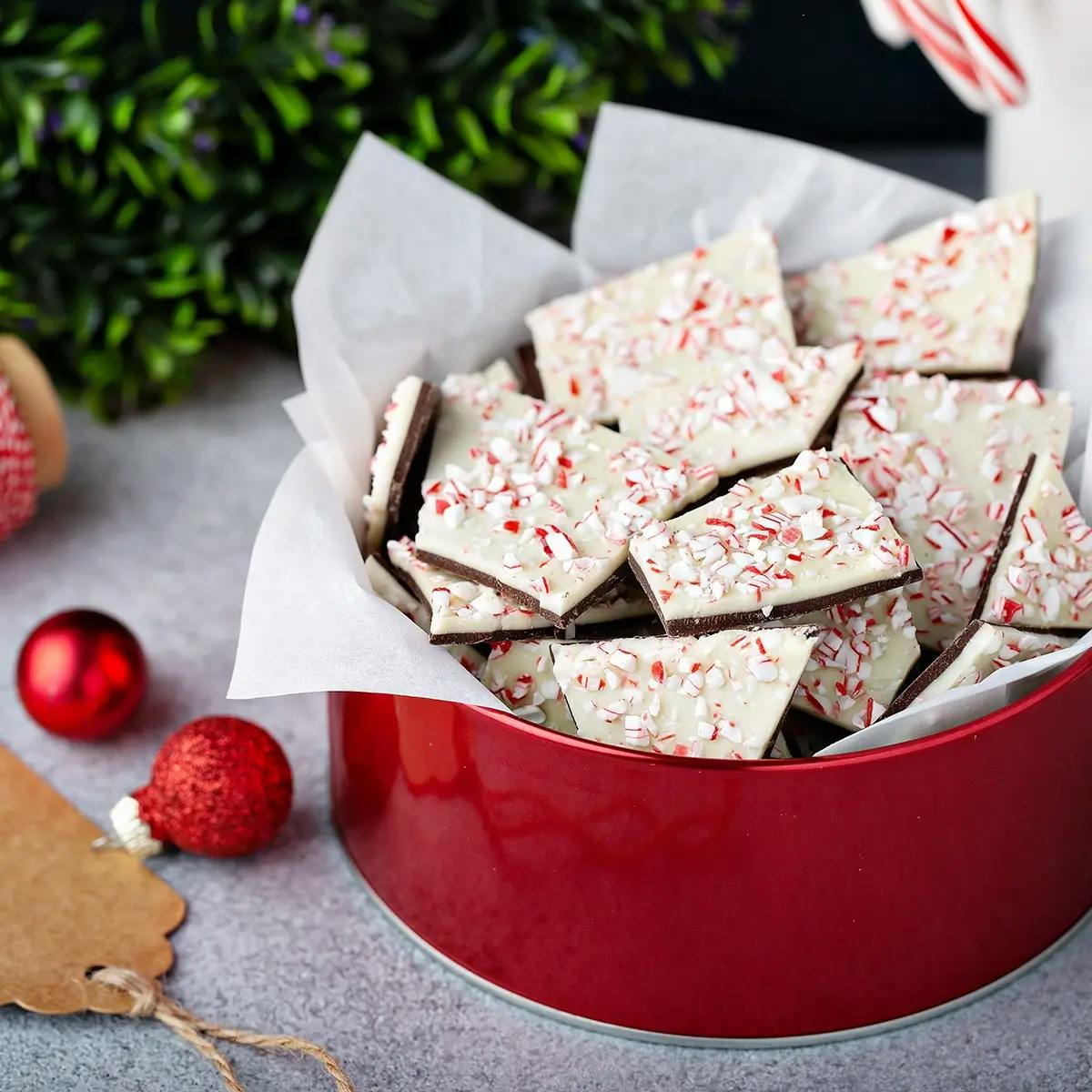 Red tin containing homemade Christmas peppermint bark with white chocolate.