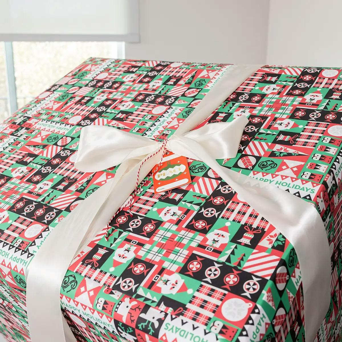 A large box wrapped with SANTA.COM branded wrapping paper and tied with white ribbon.