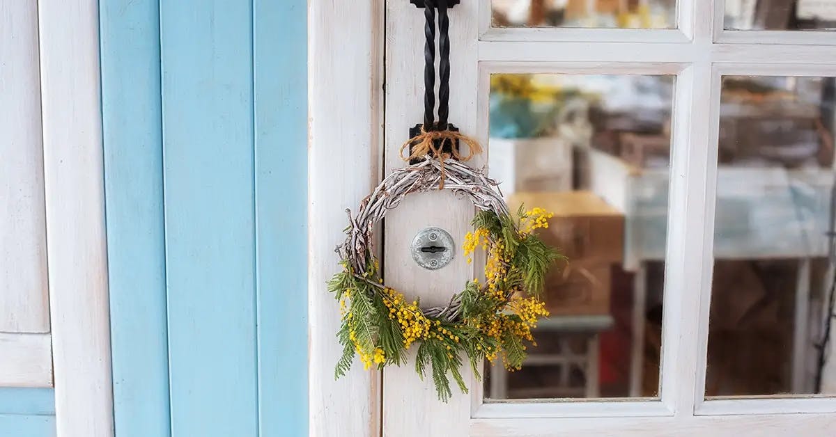 Rustic Christmas wreath with yellow flowers, hanging on door knob.