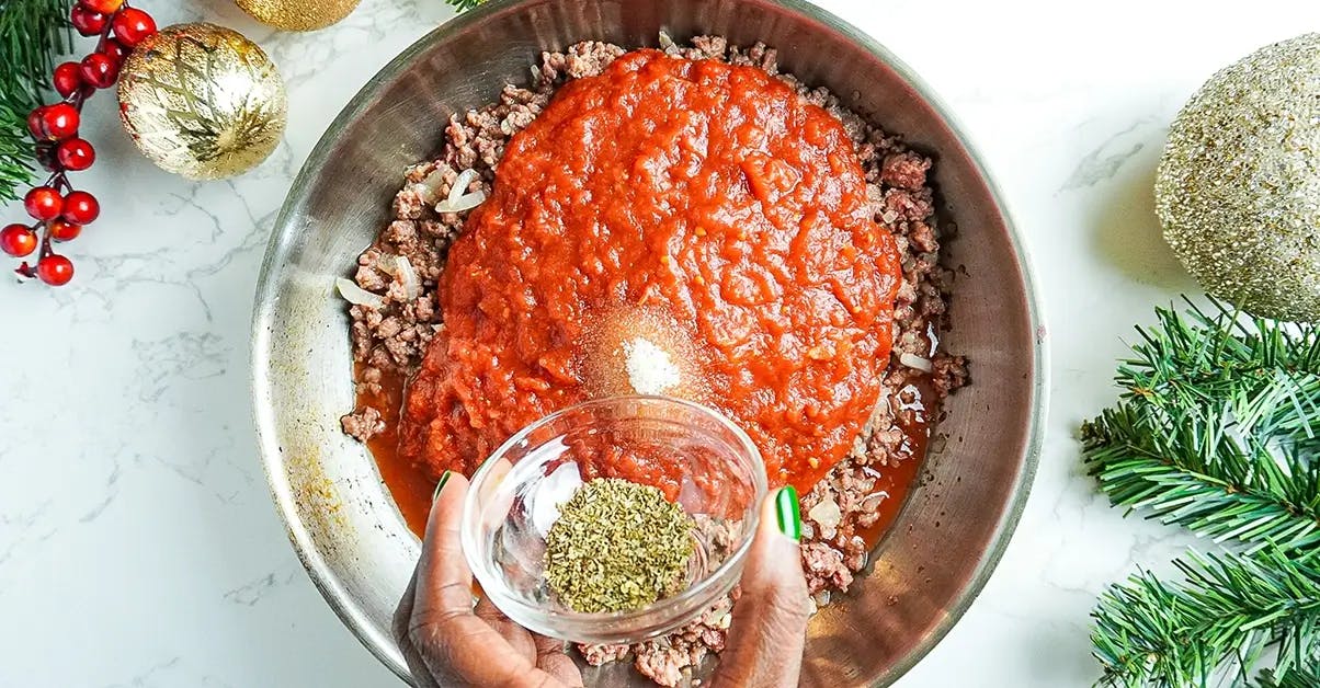Adding seasoning and tomato sauce to the sauce for a vegetarian lasagne.