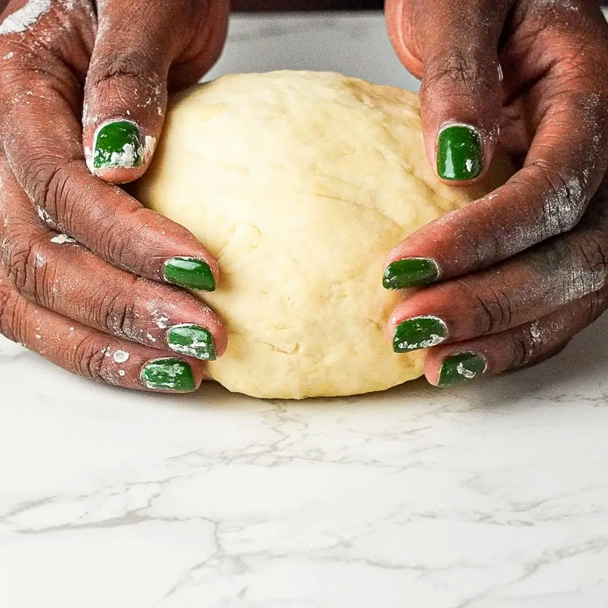 Hands holding homemade dough for vegetarian lasagne recipe.